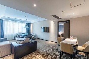 A modern hotel room with a living area, dining table, and a flat-screen TV. - Duoman Hotel (Dongguan Xiping Metro Station) (Dongguan)