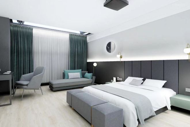 Quarto de hotel moderno com cama, escrivaninha, cadeira e sofá.
