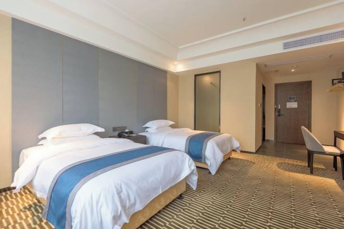 A hotel room with two beds, a desk, and a chair.