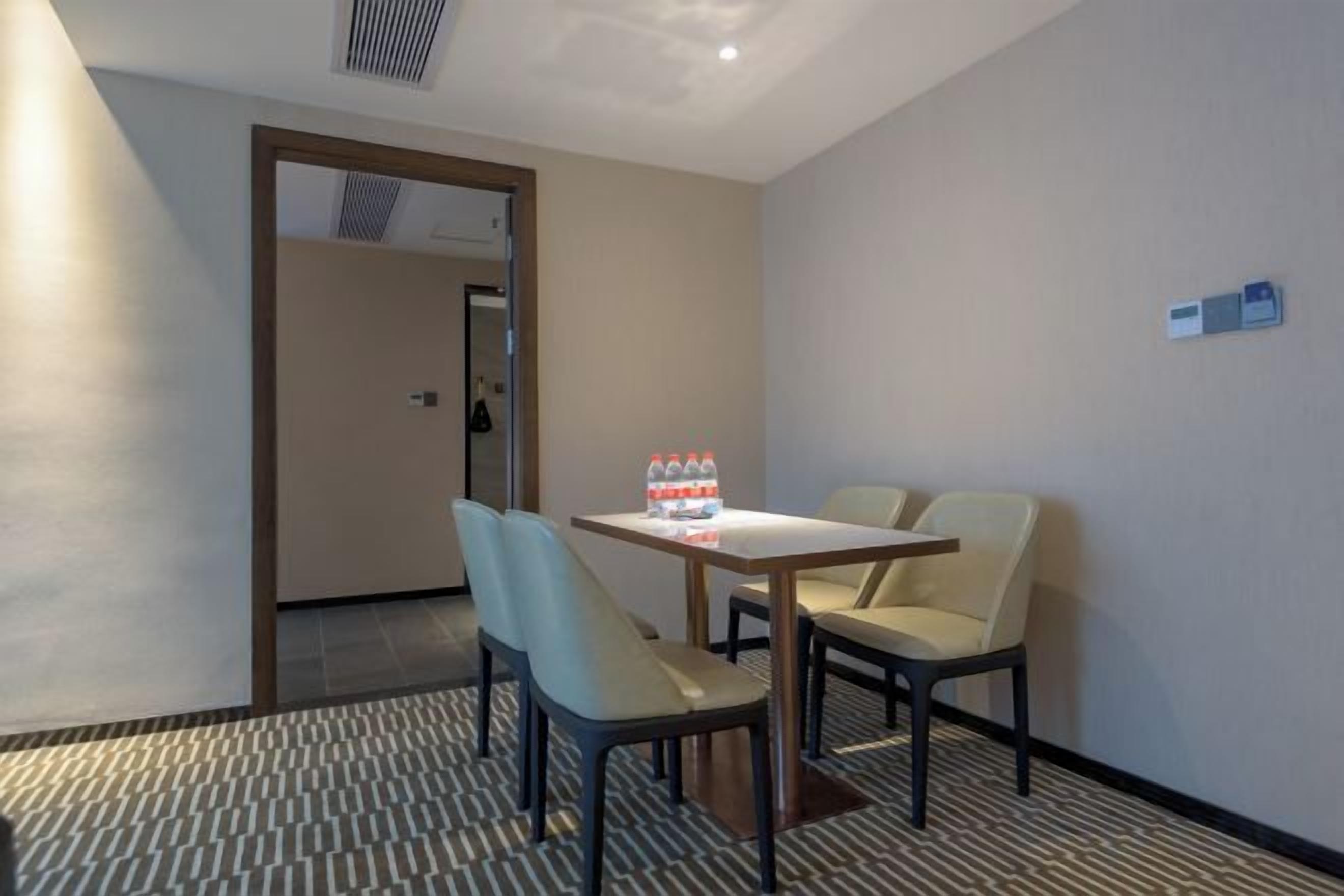 Une chambre d’hôtel avec une table à manger, deux chaises et une bouteille d’eau posée sur la table.