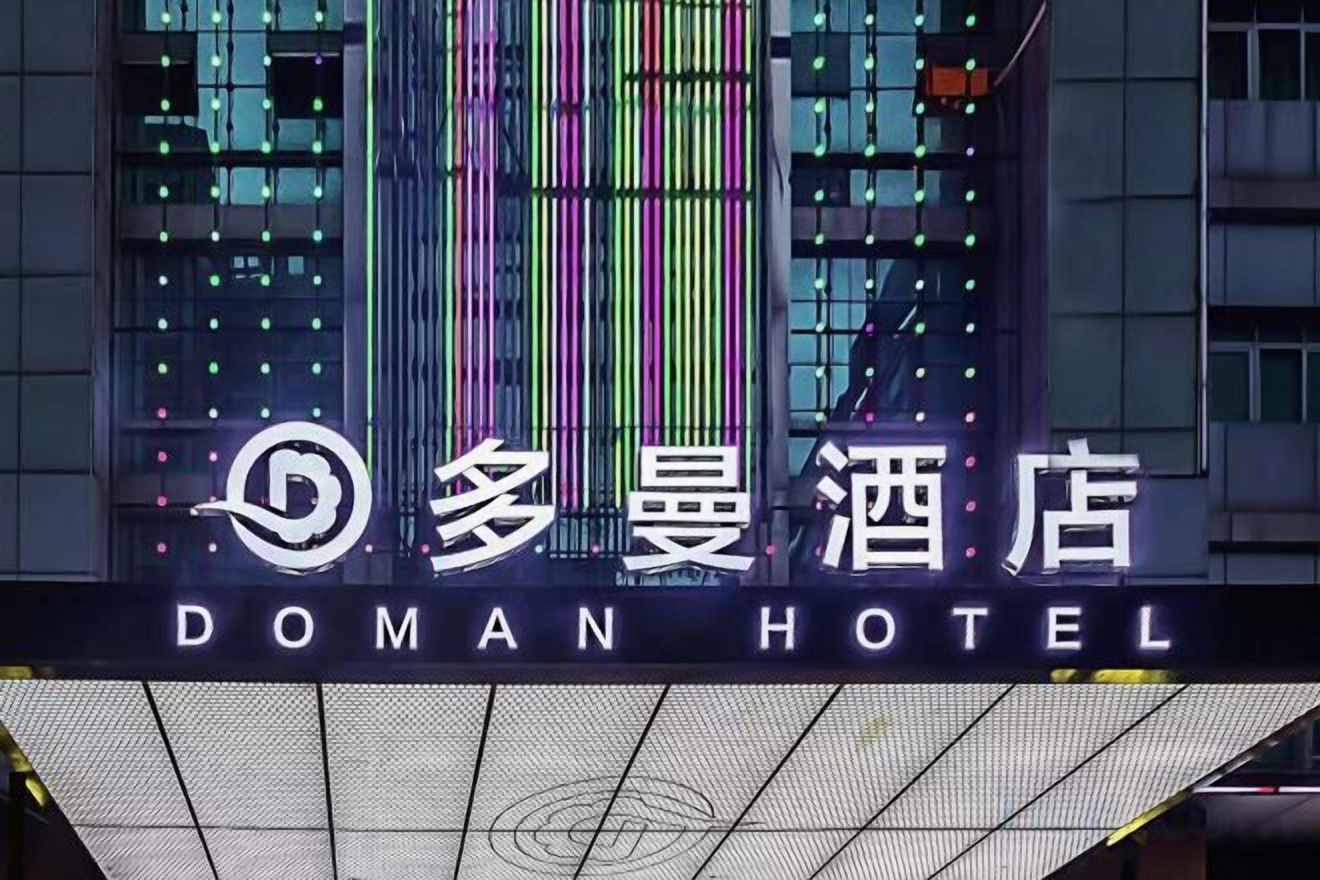 Un letrero de hotel con el nombre 'DOMAN HOTEL' y un logotipo estilizado en la parte superior.