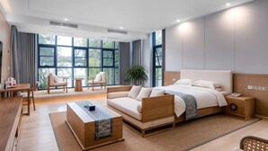A modern hotel room with a large bed, a sofa, a coffee table, and a desk. - Duoman Hotel (Dongguan Xiping Metro Station) (Dongguan)