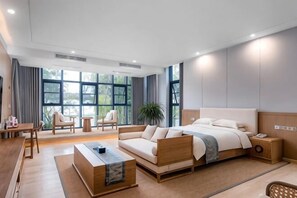 A modern hotel room with a large bed, a sofa, a coffee table, and a desk. - Duoman Hotel (Dongguan Xiping Metro Station) (Dongguan)