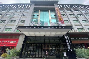 L’entrée d’un hôtel, avec une grande enseigne indiquant « DOMAN HOTEL » et une enseigne verticale affichant des caractères chinois.
