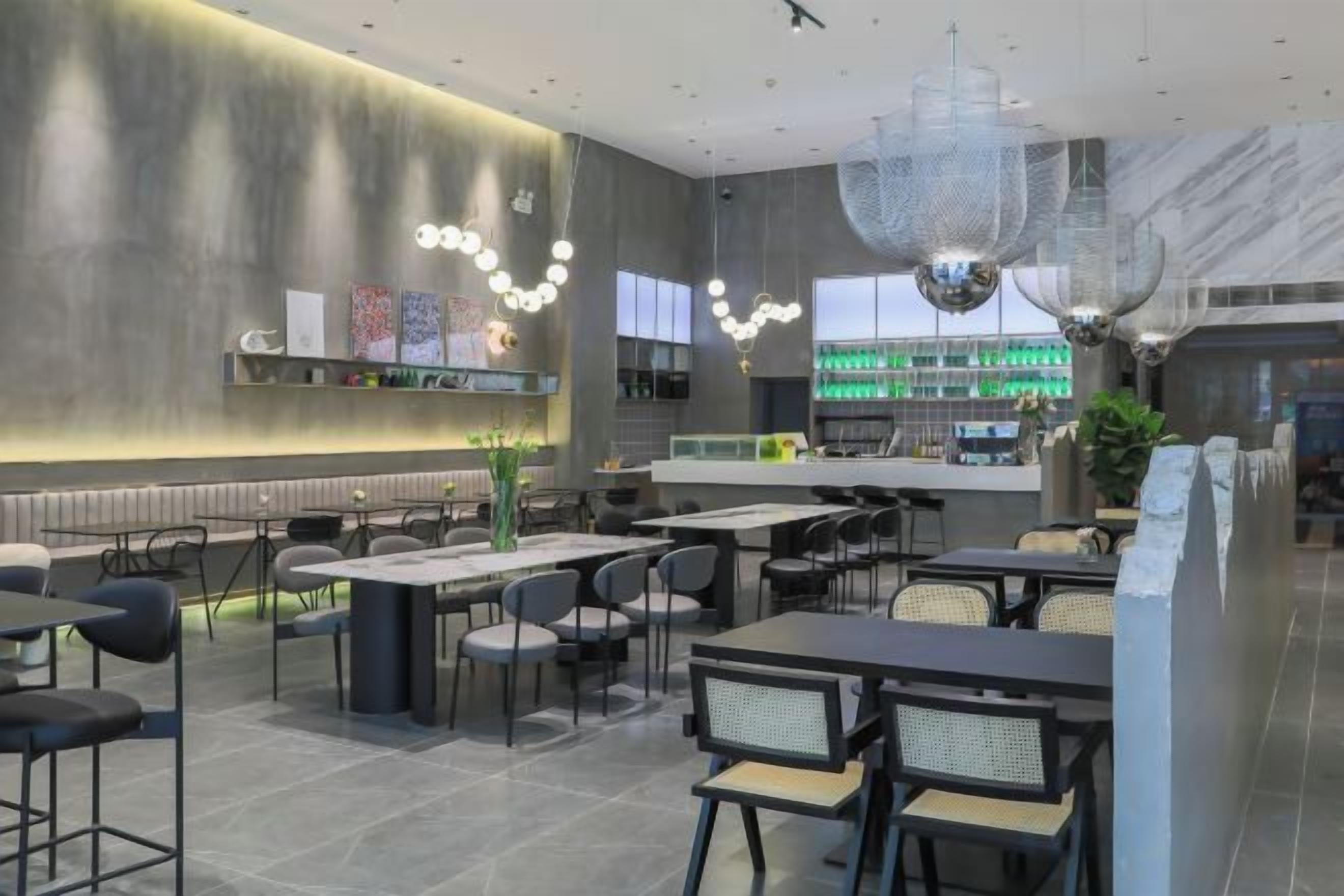 Ein modernes Restaurantambiente mit hohen Tischen, Stühlen und einer Bar.