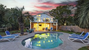 Uma casa de dois andares com piscina e área de estar ao ar livre.