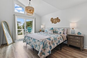 Un dormitorio con cama, mesitas de noche, una lámpara colgante y vistas a través de una puerta de vidrio.