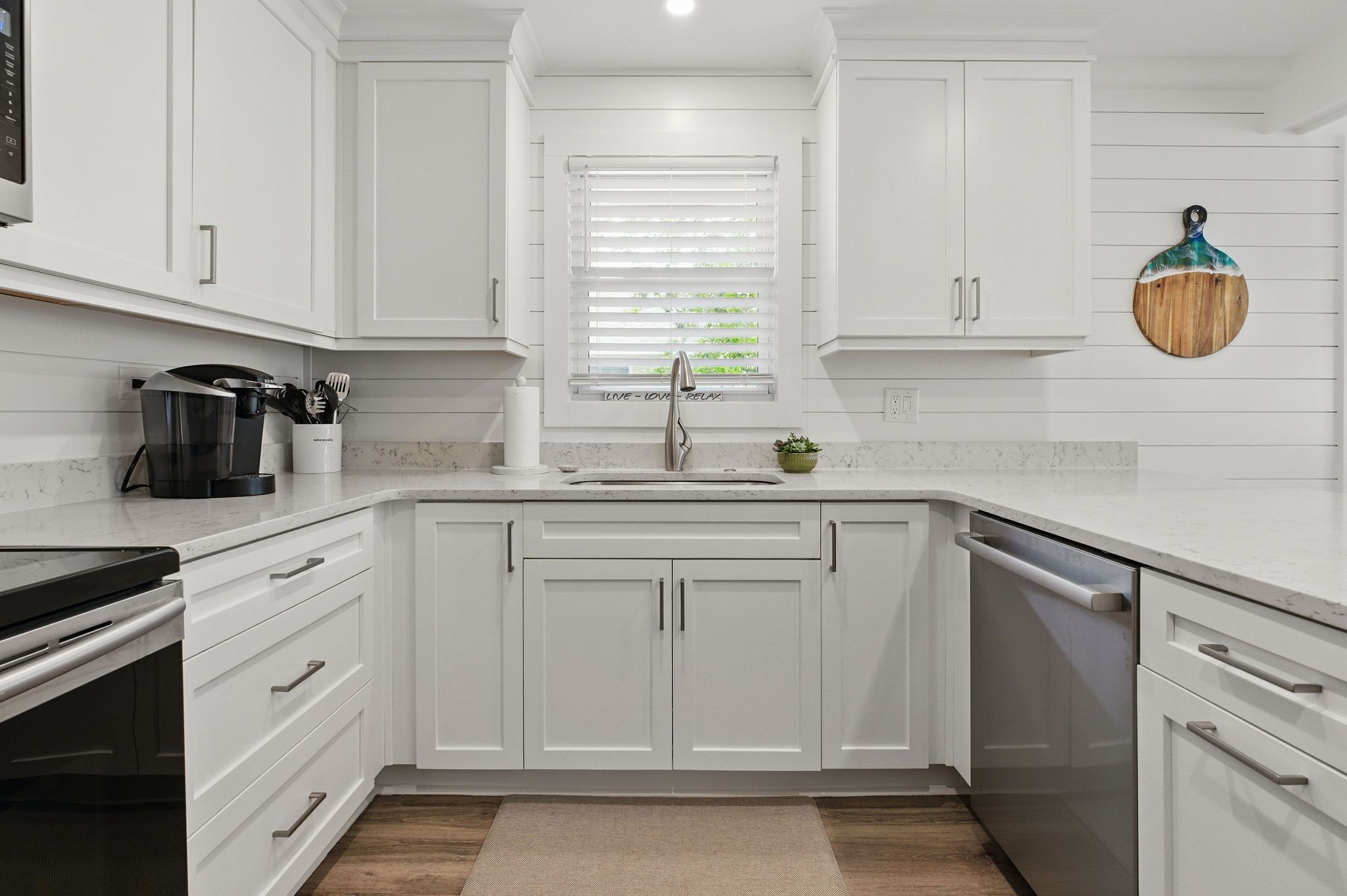 A modern kitchen with white cabinetry, a built-in oven, and a dishwasher.