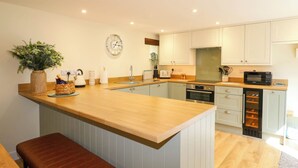 Una cocina moderna con encimera de madera, horno integrado y microondas.
