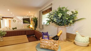 Un salón con una mesa de madera, un sofá, una planta grande en maceta y una botella de champán.