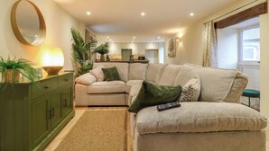 Una sala de estar con un sofá color beige, un mueble verde y un espejo grande.