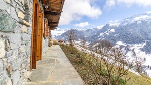 A stone building with wooden doors and a stone pathway leading to a mountain view.