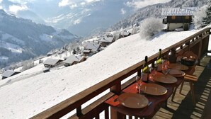 A snow-covered mountain village with wooden buildings and a wooden deck overlooking the village.