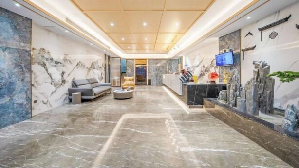 A modern hotel lobby with marble flooring, a sofa, a coffee table, and a reception desk with a TV. - Yimi Collection Hotel (Shanghai Xizang North Road Subway Station) (Shanghai)