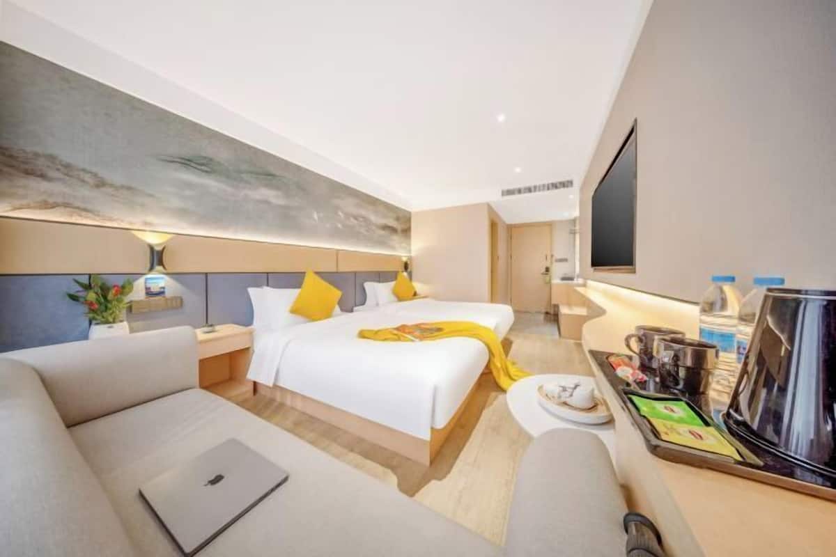 A hotel room with a bed, a sofa, a coffee station, and a TV.