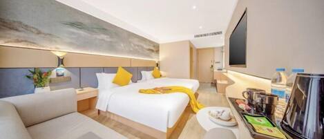 A hotel room with a bed, a sofa, a coffee station, and a TV.