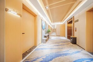 A hotel hallway with a marble floor, a reception desk, and an elevator. - Yimi Collection Hotel (Shanghai Xizang North Road Subway Station) (Shanghai)