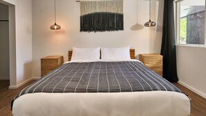 A modern bedroom with a large bed, two bedside tables, a wall-mounted tapestry, and pendant lighting. - One-bedroom suite, Mt Hood views, downtown White Salmon, suite 28 (White Salmon)