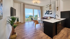 A modern kitchen with a large island, a black refrigerator, and a view of a mountain through the window. - One-bedroom suite, Mt Hood views, downtown White Salmon, suite 28 (White Salmon)