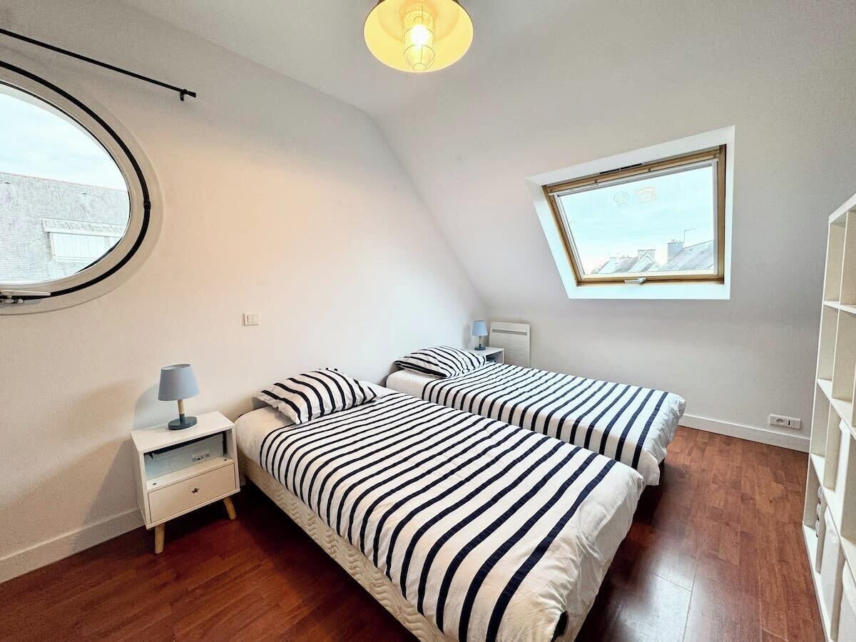A bedroom with two beds, a window, a lamp, and a ceiling light.