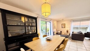 A dining area with a wooden table and chairs, a black cabinet with glass doors, and a yellow pendant light.