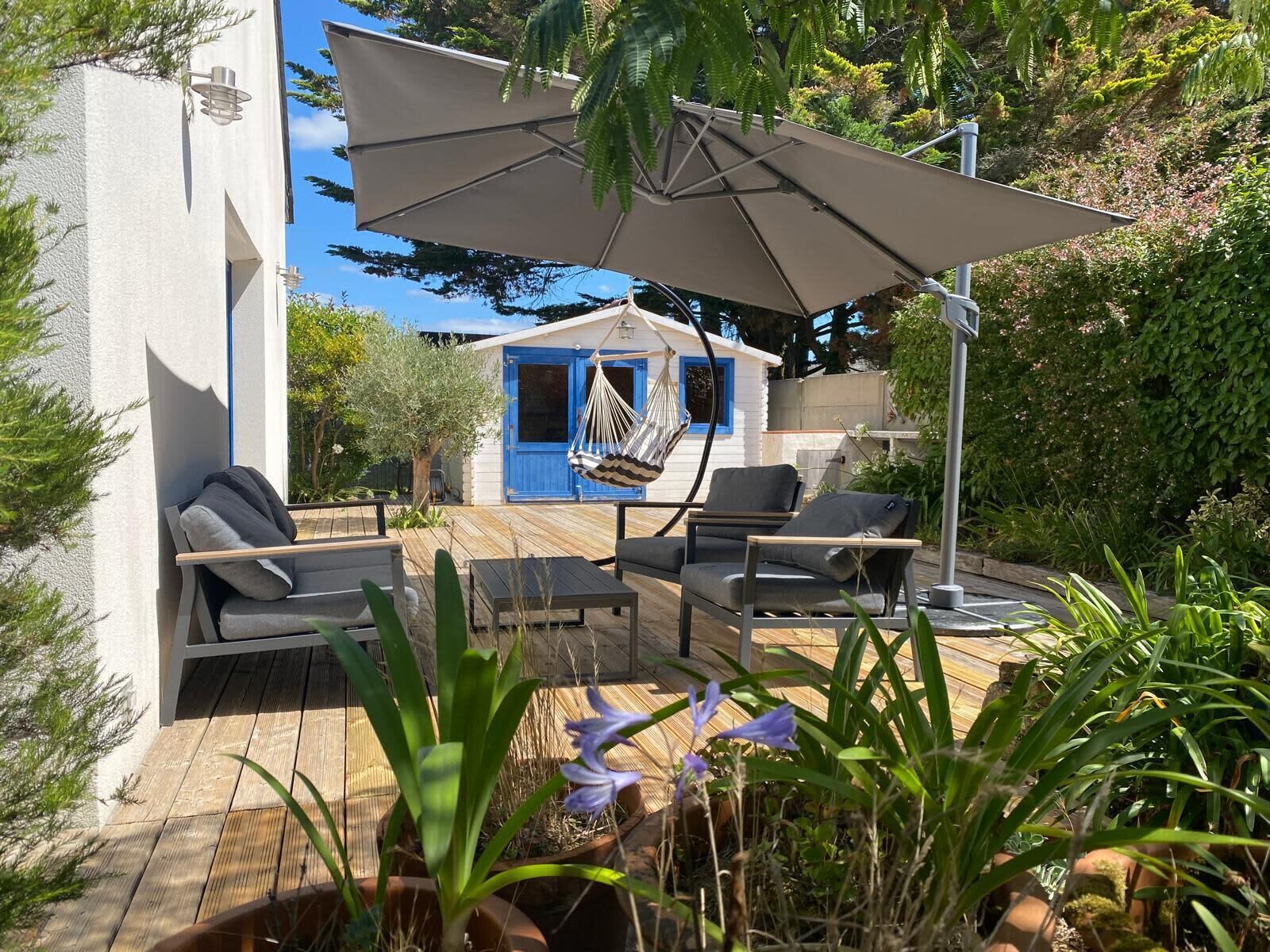 A wooden deck with outdoor furniture, a hanging chair, and a blue door.