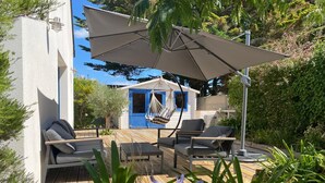 A wooden deck with outdoor furniture, a hanging chair, and a blue door.