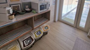 A kitchen with a microwave, shelves with kitchenware, and a window with a view of the outside. - marte rooms (San Nicola)