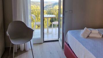 Une chambre à coucher avec un lit, une chaise et un balcon offrant une vue.