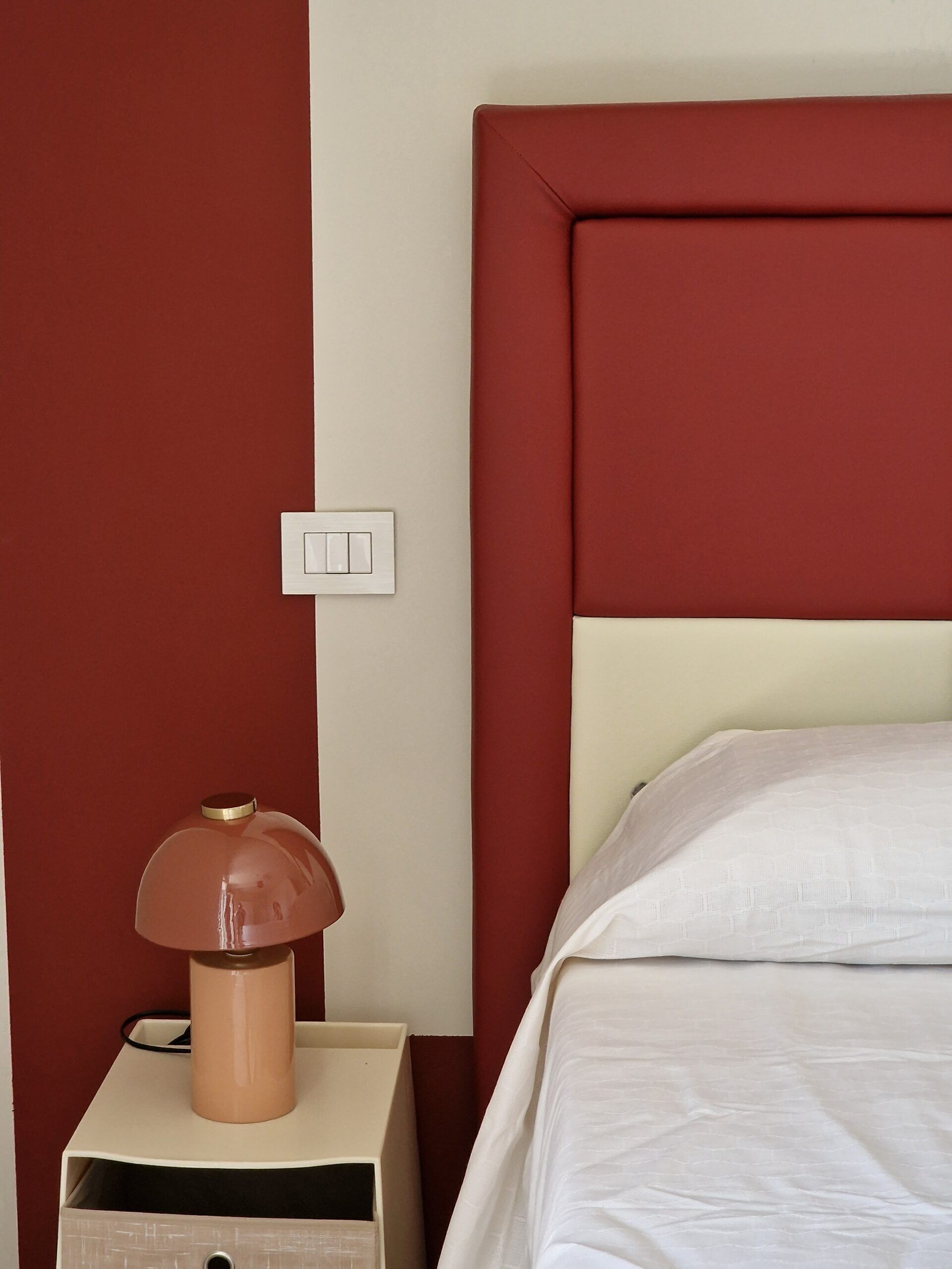 A neatly made bed with a white comforter and a red headboard.