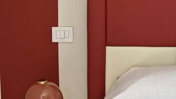 A neatly made bed with a white comforter and a red headboard.
