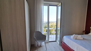 A bedroom with a bed, a chair, and a sliding glass door leading to an outdoor balcony. - marte rooms (San Nicola)