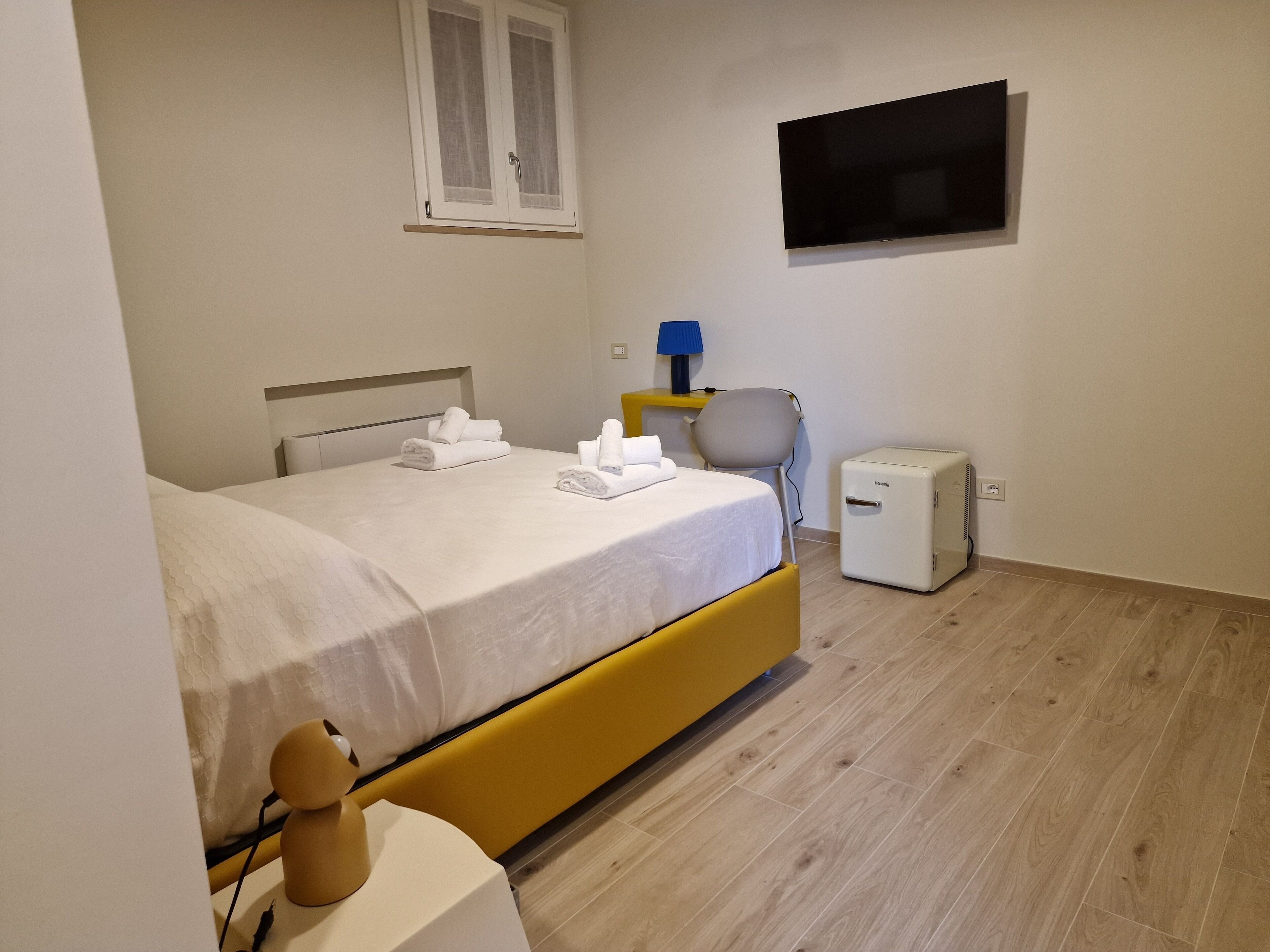 Habitación de hotel con cama, un escritorio pequeño, una silla, televisor y calefacción.