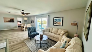 A spacious living room with a large sofa, a coffee table, and a dining area with chairs. - The Lighthouse in Fort Myers Beach (Fort Myers Beach)