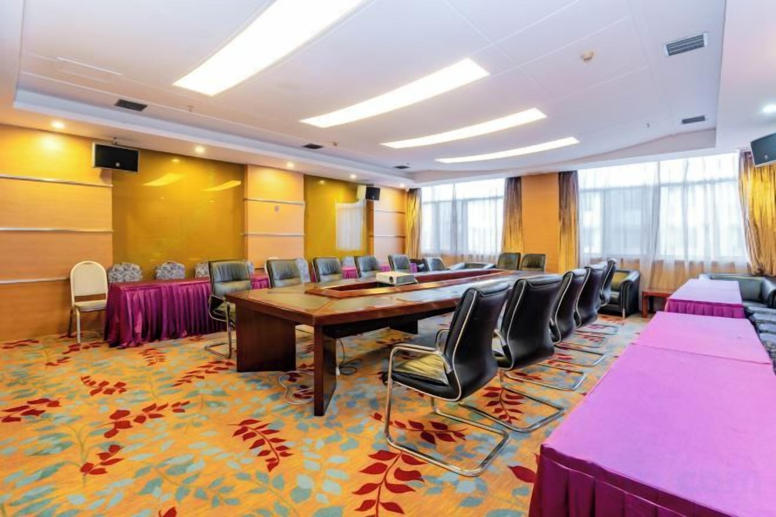 A conference room with a long table, chairs, and a carpeted floor.