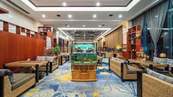 A hotel lobby with a central aquarium, seating areas, and a patterned carpet.
