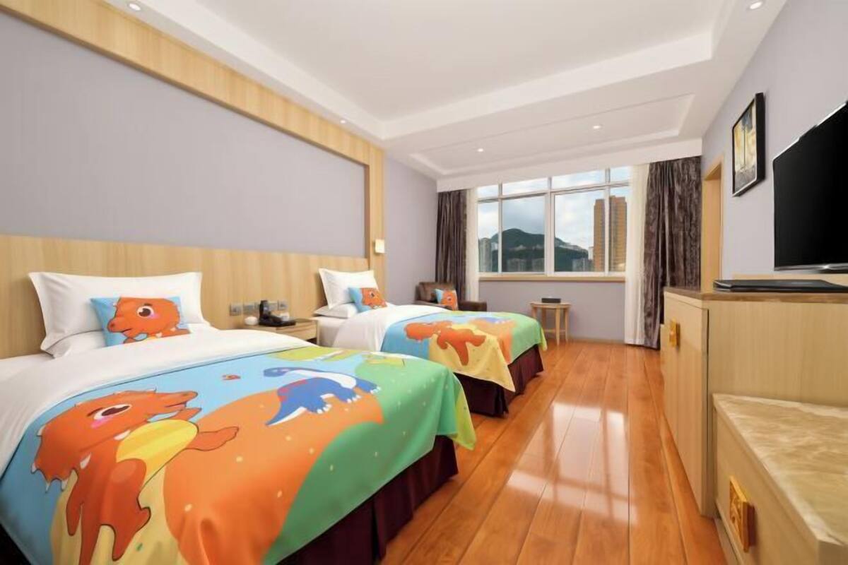 Habitación de hotel con dos camas, televisión, ventana con vistas y suelo de madera.