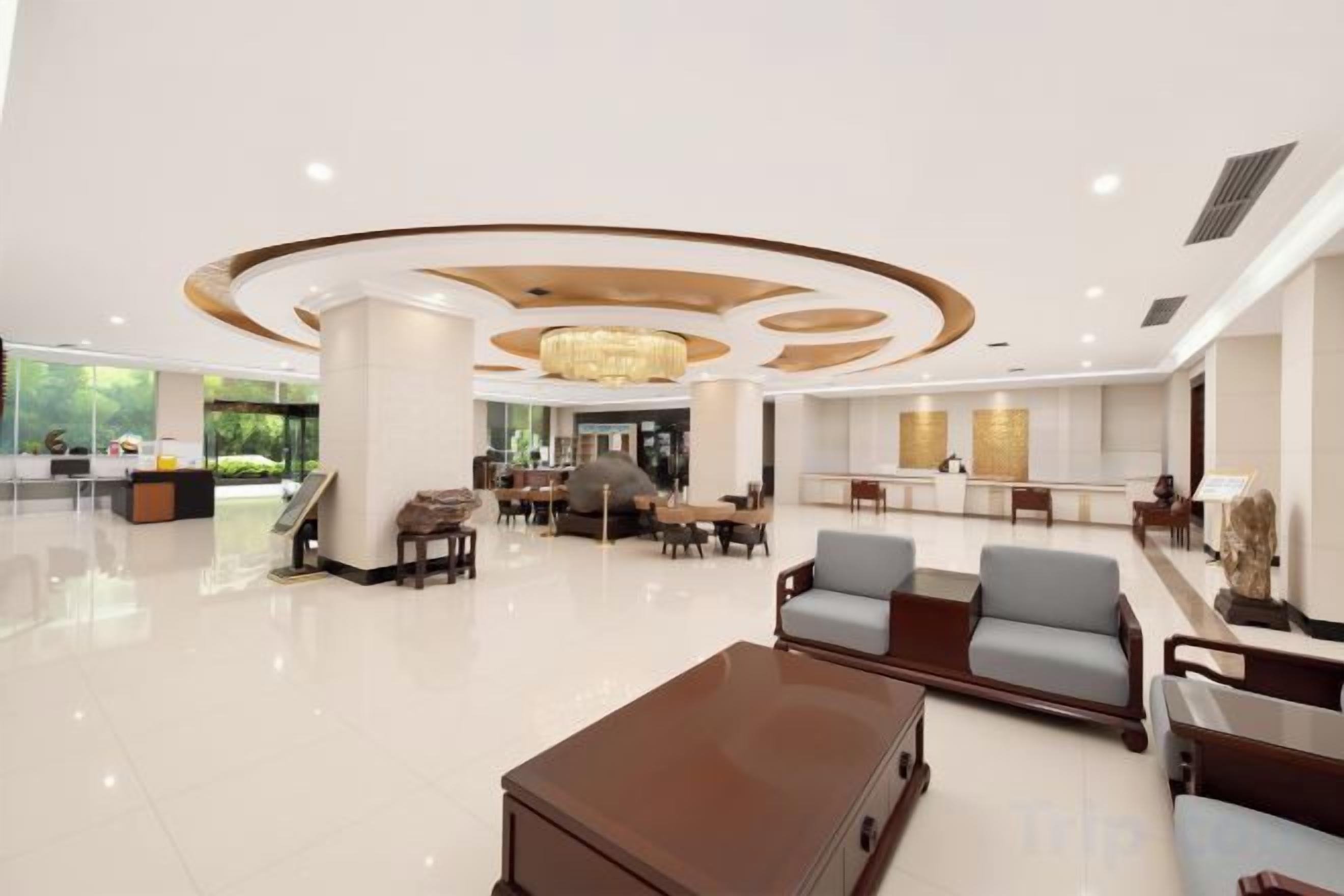 A spacious lobby with a reception desk, seating area, and a chandelier.