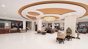 Un hall d’entrée spacieux, agrémenté d’un lustre moderne, de coins salon et d’un escalier.