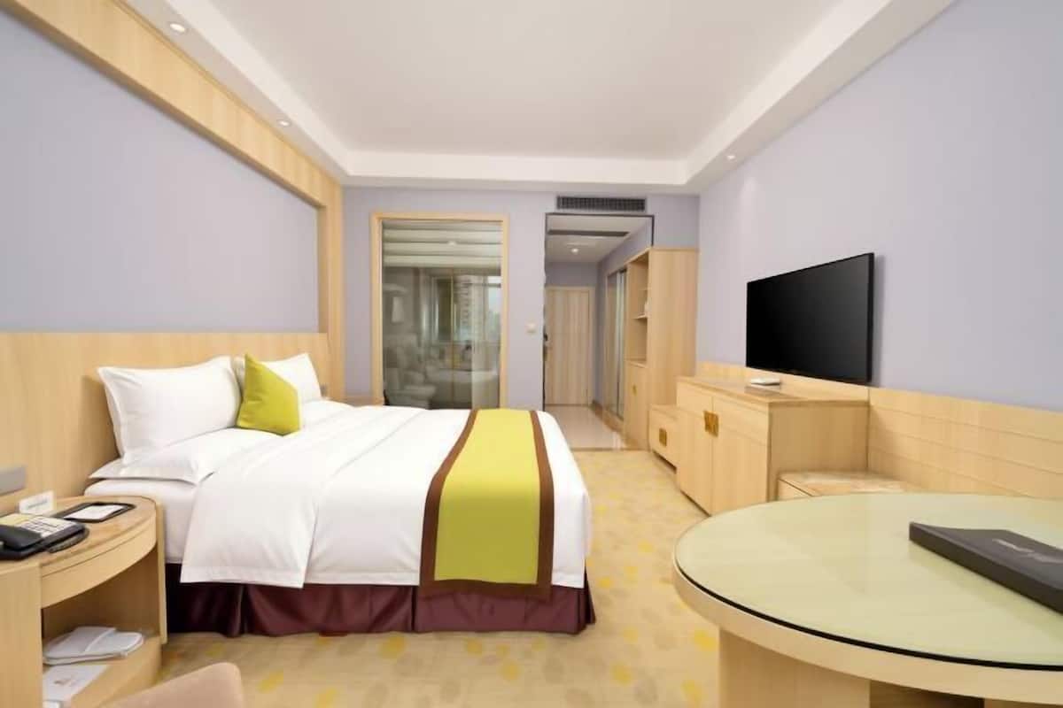 Una habitación de hotel con cama, mesita de noche, televisor y una mesa redonda.