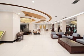 Um hall amplo com balcão de recepção, área de estar e um lustre.