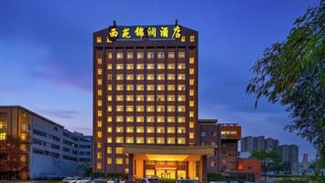 A multi-story hotel with a prominent entrance and a parking lot in front.
