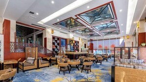 Un hall d’entrée spacieux avec un plafond haut, un mobilier moderne et un bar central.