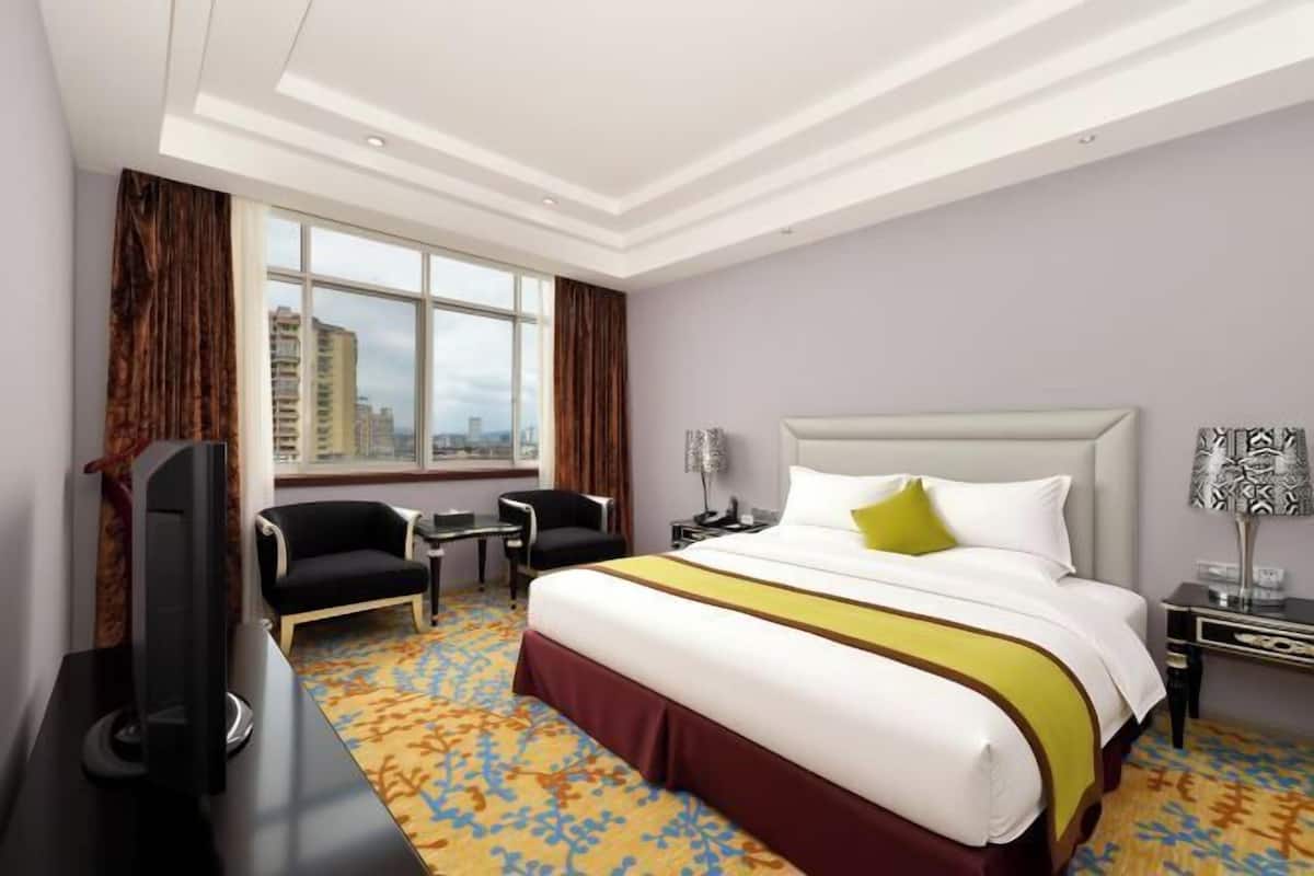 Una habitación de hotel con una cama grande, televisión, escritorio y una silla.