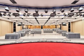 A conference room with multiple tables and chairs, a stage with a red carpet, and a ceiling with lighting fixtures. - Xiyuan Jinrun Hotel (Guiyang Huaxi Xiaohe Branch) (Guiyang)