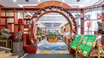 Uma casa de chá tradicional chinesa com uma entrada em arco, área de exposição central e diversos itens relacionados ao chá em prateleiras.