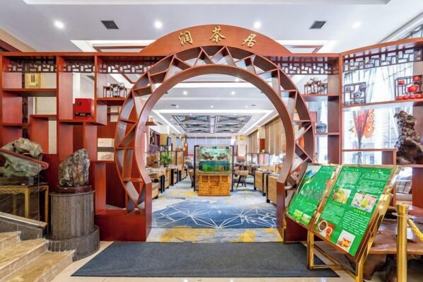 A traditional Chinese tea house with an archway entrance, a central display area, and a variety of tea-related items on shelves.