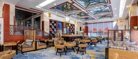 A hotel lobby with seating areas, a reception desk, and a large glass ceiling.