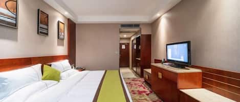 A hotel room with a bed, a television, a desk, and a door leading to another room.
