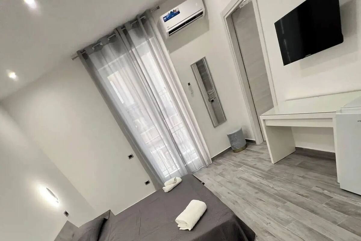 Et moderne hotelværelse med seng, skrivebord og fladskærms-tv.